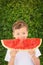 Happy child boy is eating a red juicy, tasty  watermelon. Caucasian kid smiling and having fun. Concept of healthy food.