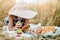 Happy child with bread in yellow autumn wheat field. A field with mature ears.girl sits on a bedspread, fresh fruits and