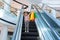 The happy child with color packages on the escalator, in shop of shopping center