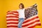 Happy child, cute girl with American flag on yellow studio background. USA celebrate July 4th, independence Day.