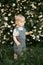 a happy child dressed in a muslin jumpsuit is resting on the green grass.