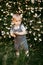 a happy child dressed in a muslin jumpsuit is resting on the green grass.