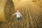 Happy child on field with bales harvest. Kid in a field with haystack. A healthy happy child in harmony with nature.