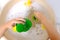 Happy child, girl 3 years old plays with rubber green, yellow ducks for swimming, child`s toy in soapy foam, concept of bathing i