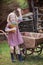 Happy child girl with bluebells in spring garden near wheelbarrow