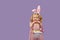 Happy child girl in costume Easter bunny rabbit with ears and a basket with eggs. Little girl on a purple