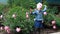 Happy Child girl dances in the garden with peonies.