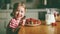 happy child girl drinks milk and eats strawberries in summer home kitchen