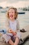 Happy child girl fooling and playing with toy bird on summer seacost