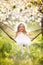 Happy child girl in hammock in spring garden