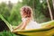 Happy child girl having fun and relaxing in hammock in summer