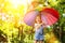 Happy child girl laughs and plays under summer rain with an umbrella