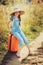 Happy child girl with orange suitcase traveling alone on summer vacation. Kid going to summer camp.