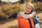 Happy child girl with orange suitcase traveling alone on summer vacation. Kid going to summer camp.