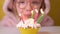Happy child girl in pink Overalls blows out five candles on birthday cake at party. Close up on girl face. Slow motion