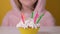 Happy child girl in pink Overalls blows out five candles on birthday cake at party. Close up on girl face. Slow motion