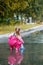 Happy child girl with pink rubber pants and boots in puddle on an autumn walk, seasonal fun childhood game