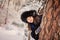 Happy child girl playing hide and seek in winter forest