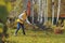 Happy child girl playing little gardener in autumn and picking leaves into basket. Seasonal garden work