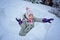 Happy child girl playing in snow castle in dropping snowballs