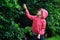 Happy child girl playing under the rain in summer garden