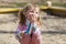 Happy child girl plays with toys in a sandbox, smile, cover your mouth with your hand