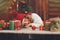 Happy child girl in red hat and scarf wrapping Christmas gifts at cozy country house, decorated for New Year and Christmas