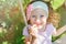 Happy child girl smells flower on swing in summer