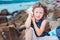 Happy child girl in stripe hat playing on the beach and listen to sea shell