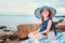 Happy child girl in stripe hat playing on the beach and listen to sea shell