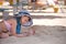 Happy child girl in swimsuit playing with sand under umbrella shadow during summer tropical vacations