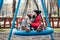 Happy child girl on swing. Little girl on a swing hugs her dog.