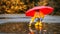 Happy child girl with umbrella and paper boat in puddle in a