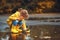 Happy child girl with umbrella and paper boat in puddle in a