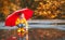 Happy child girl with umbrella and paper boat in puddle in a