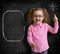 Happy child in glasses standing near school chalkboard with bulb