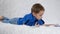 A happy child happily reads a book lying on a white sofa. The concept of child development