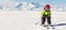 Happy child with helmet and goggles on the ski slopes at high altitude..In the background the Alps