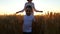 A happy child and his mother are running across a field of wheat during sunset. Camera movement steadicam.