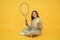 happy child hold badminton racquet and drink water from bottle on yellow background, health.