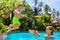 Happy child jump to mother hands in swimming pool