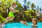 Happy child jump to mother hands in swimming pool