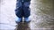 Happy child jumping in puddle in waterproof coat. A boy have fun in the rain weather in a bright raincoat. Legs of child with rubb