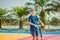 Happy child on kick scooter in on the basketball court. Kids learn to skate roller board. Little boy skating on sunny