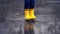 Happy child legs in yellow rubber boots dance and jump in small puddle