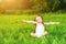 Happy child little girl spread his arms in white dress lying on