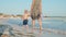 Happy child looking around at seashore. Unrecognizable woman walking at seaside.