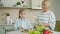 Happy child making salad then doing high-five with elderly granny at kitchen table at home