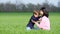 Happy child and mom play on the green grass in the park, hug and kiss