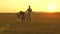 Happy child and parents walk at sunset. Dad hugs daughter and whirls in flight. Silhouette of a family walking in the